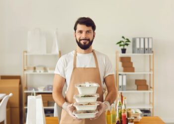 a food handler fills two containers with sliced tomatoes for sandwiches later in the week